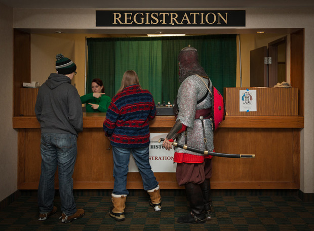 Two visitors and a reenactor at a registration desk