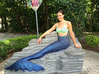 Ali standing behind a mermaid tail photo prop